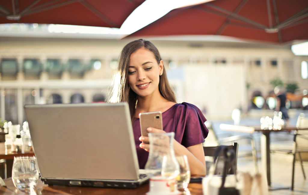 Una donna che guarda un telefono cellulare con un'espressione di soddisfazione, rappresentando la raggiunta visibilità online e il successo del proprio business.